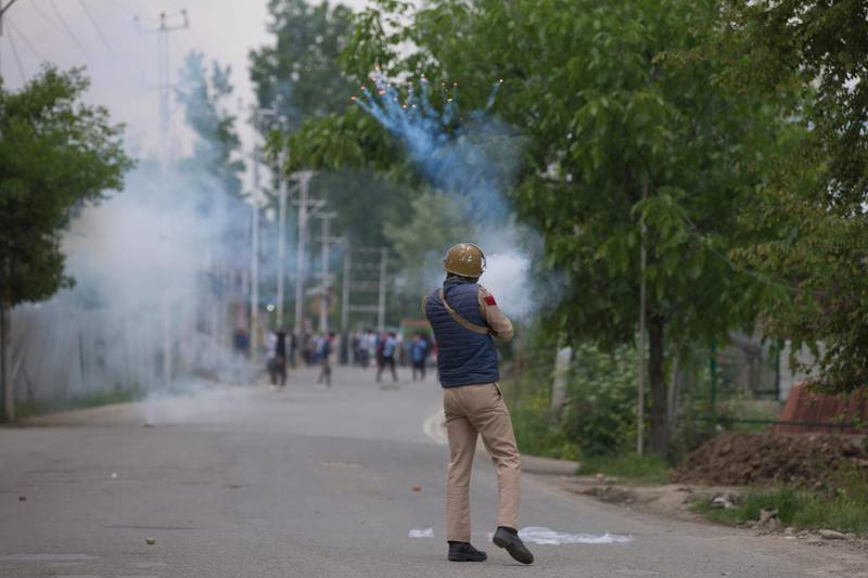 An  Indian police man fires tear gas shell at Kashmir protesters near the site of a gunbattle in Pulwama, south of Srinagar, Indian controlled Kashmir, Thursday, May 16, 2019. Three rebels, an army soldier and a civilian were killed early Thursday during a gunbattle in disputed Kashmir that triggered anti-India protests and clashes, officials and residents said. (AP Photo/ Dar Yasin)