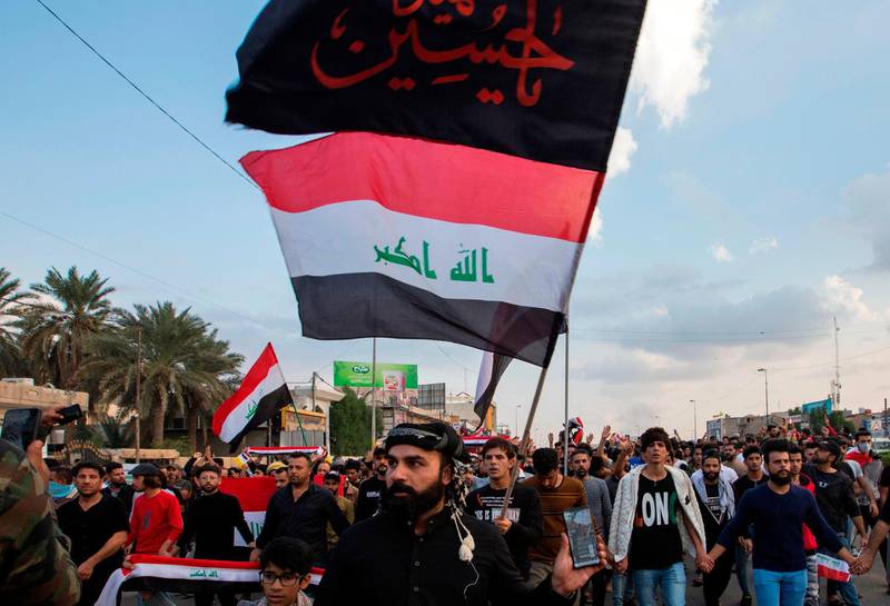 Iraqi protesters march with national flags and a Shiite Muslim flag reading in Arabic "oh martyr Hussein" during an anti-government demonstration in the southern Iraqi city of Basra. AFP