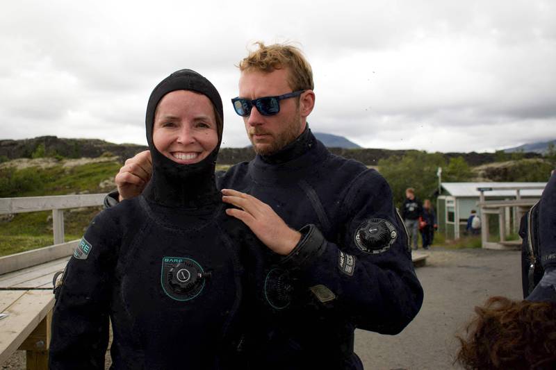 Diving instructor Lorenzo (R) helps a Canadian tourist (L) to put on her hood before a snorkelling tour on July 26, 2022 in Thingvellir, Iceland.  - In between North American and Eurasian tectonic plates, Iceland's Silfra fissure is one of the world's most famous dive sites, popular with tourists who venture into its icy waters.  (Photo by Jeremie RICHARD  /  AFP)  /  TO GO WITH AFP STORY BY JEREMIE RICHARD