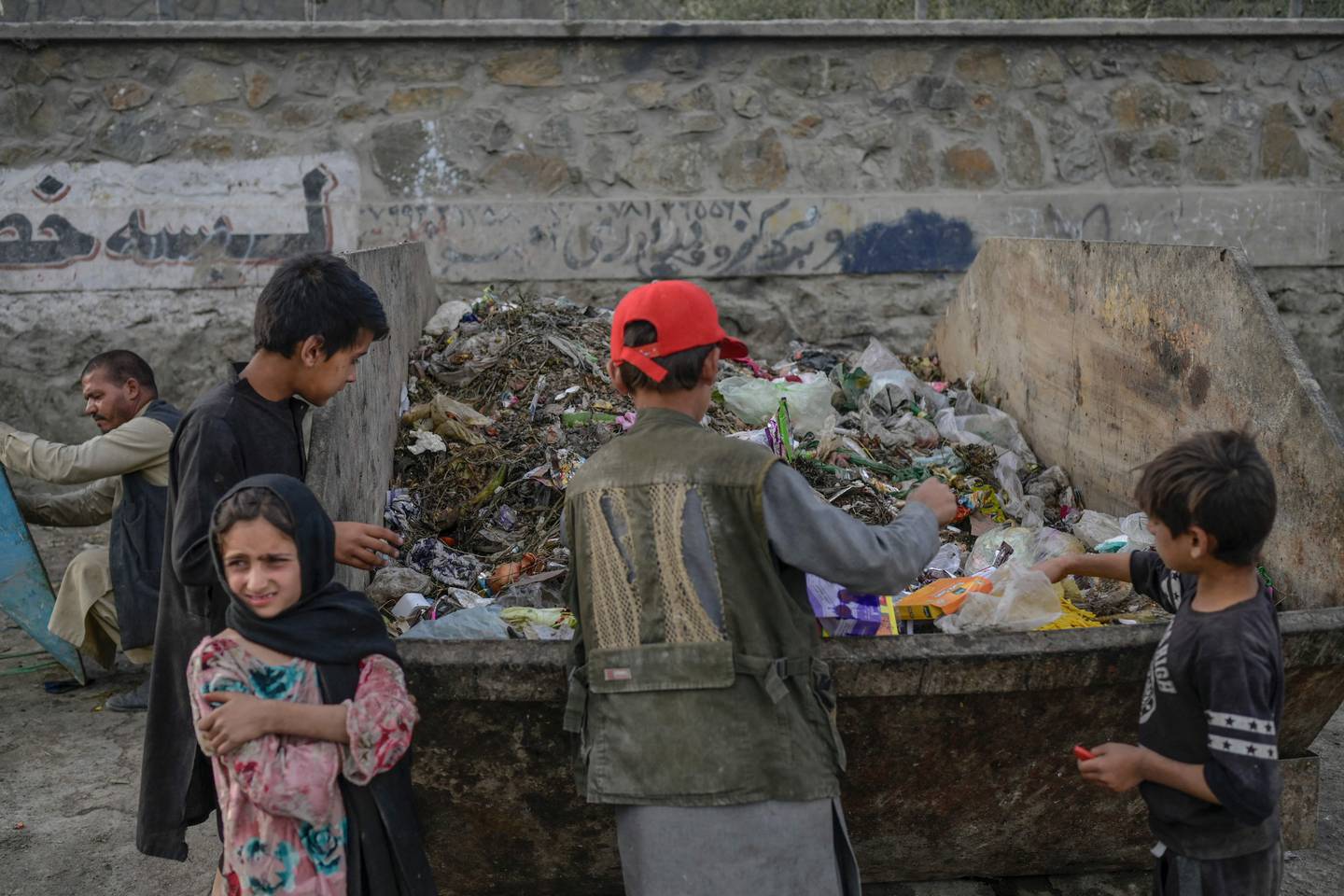 Children collect food and recyclable materials from waste near the airport in Kabul. AFP 