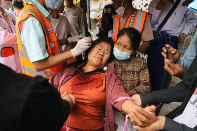A protester has a wound on her head treated after being beaten by security forces during a demonstration against the military coup in Mandalay. AFP