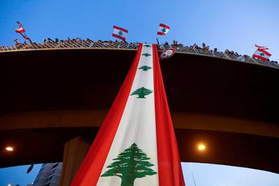 FILE PHOTO: Demonstrators stand on a bridge decorated with a national flag during an anti-government protest along a highway in Jal el-Dib, Lebanon October 21, 2019. REUTERS/Mohamed Azakir/File Photo