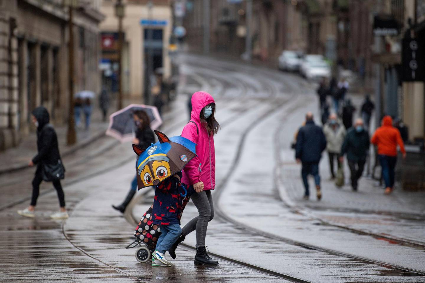 Many people wearing face masks as they move along a shopping street as rain falls in Nottingham, England, Tuesday Oct. 27, 2020.  The Nottingham area will move into the Tier 3 highest level of coronavirus restrictions on upcoming Thursday because of a surge in COVID-19 cases.  (Joe Giddens/PA via AP)