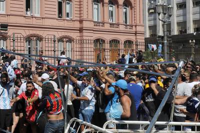 Fans try to climb over the fence to enter Casa Rosada during Diego Maradona's funeral. Getty