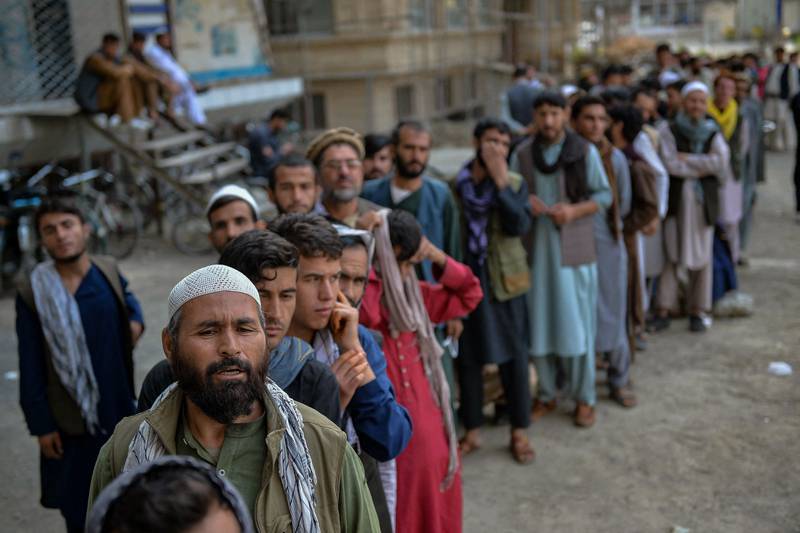 Afghans queue up as they wait for the banks to open in Kabul. If the assets remain entirely frozen, then inflation will continue to soar and Afghans will not be able to afford basic necessities  AFP