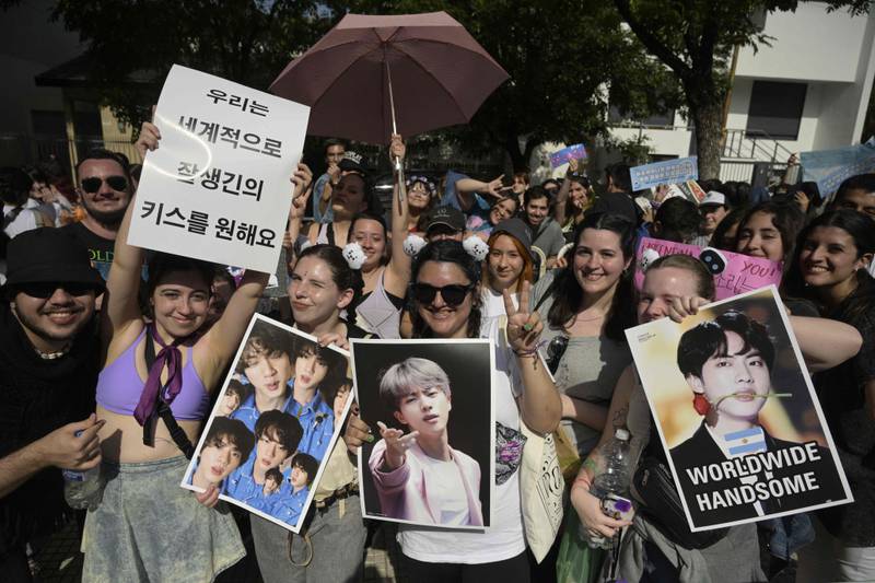 Fans hold up photos and posters for Jin.