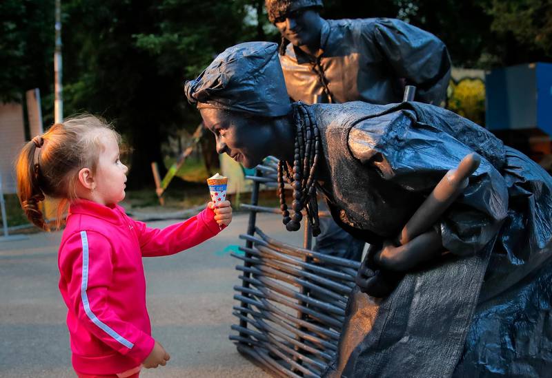 A child offers ice-cream to artists of Ukraine's Artel Myth theatre performing "A day in the life of Ukrainians" at the Living Statues International Festival, in Bucharest, Romania. Vadim Ghirda / AP Photo