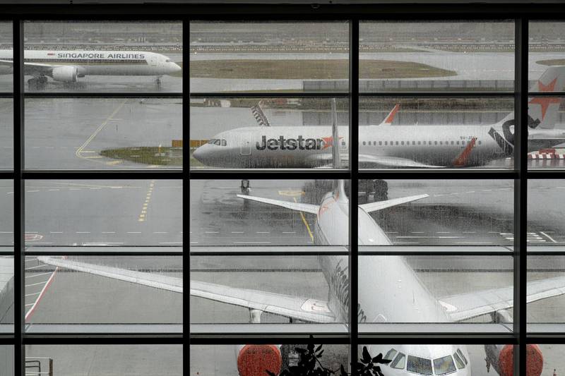 A Singapore Airlines flight goes past some Jetstar planes parked at the tarmac of Changi Airport in Singapore. Getty Images