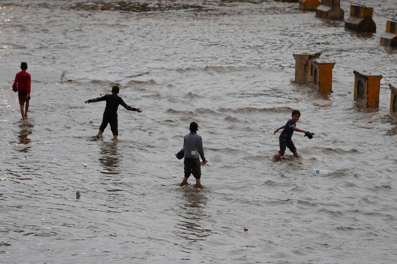 Yemeni children walk through a flooded street following heavy rains in the old quarter of Sana'a, Yemen. Heavy rains and associated floods through Yemen have left at least 16 people dead and damaged dozens of homes and roads.  EPA