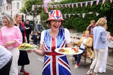 Sophie Graham carries plates of food at a Big Lunch event to celebrate the coronation of Britain's King Charles, in Napier Avenue in Fulham, London, Britain, May 7, 2023.  REUTERS / Kevin Coombs     TPX IMAGES OF THE DAY