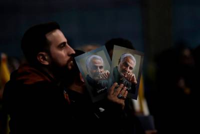 A Hezbollah supporter holds pictures of Qassem Suleimani during a ceremony marking the the end of a 40-day Muslim mourning period for the Iranian general and the anniversary of the assassination of Hezbollah leaders Abbas Al Moussawi, Ragheb Harb and Imad Mughniyeh. AP Photo