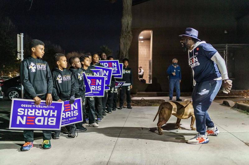 A group of kids who support presidential candidate Joe Biden hold signs on the sidewalk in front of a polling place in Minneapolis, Minnesota.  AFP