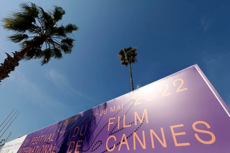 A view of a palm tree behind a giant canvas of the official poster. EPA