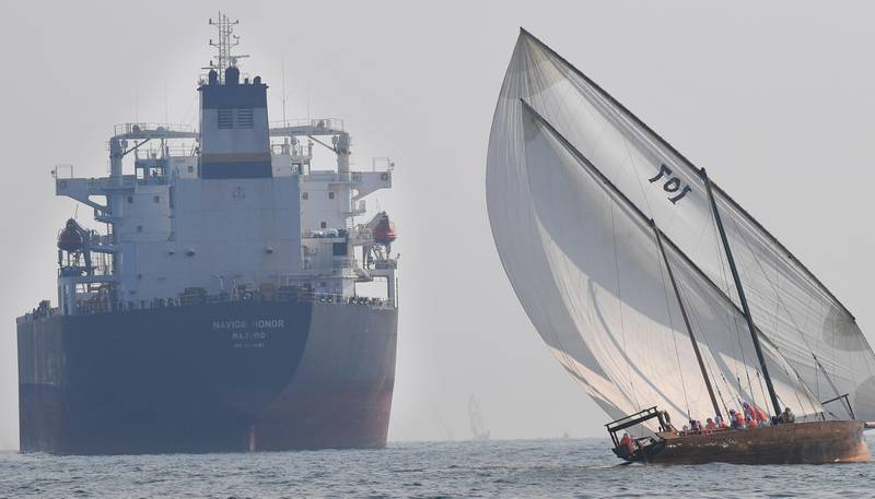 TOPSHOT - Emirati competitors sail their dhow past a crude oil tanker Navig8 Honor during the Dalma Sailing Festival in the waters of Dalma island in the Gulf, about 40 kms off of the Emirati capital Abu Dhabi, on October 22, 2019.  / AFP / KARIM SAHIB
