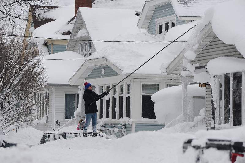 A man attempts to clear his roof of snow in Buffalo. Getty