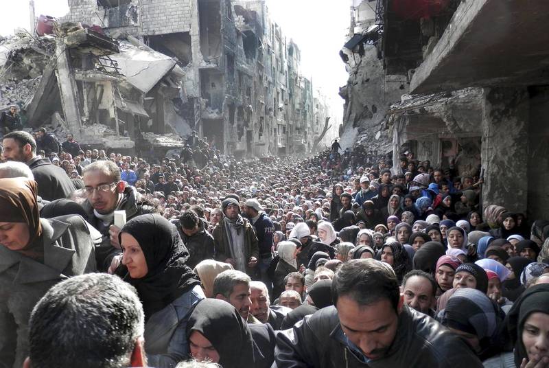 FILE - In this Jan. 31, 2014 file photo released by the United Nations Relief and Works Agency for Palestine Refugees, shows residents of the besieged Palestinian camp of Yarmouk, queuing to receive food supplies, in Damascus, Syria. Actors Hugh Grant and Viggo Mortensen are among more than 25 celebrities and public figures expressing "horror" over President Donald Trump's decision to cut funding to UNWRA. The group said in a joint statement Thursday, Jan. 25, 2018, that "the real target of this lethal attack is the Palestinian people themselves." (UNRWA via AP, File)