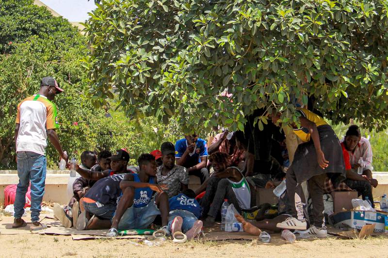Sub-Saharan migrants rest under the shade of a tree to avoid the heat. AFP