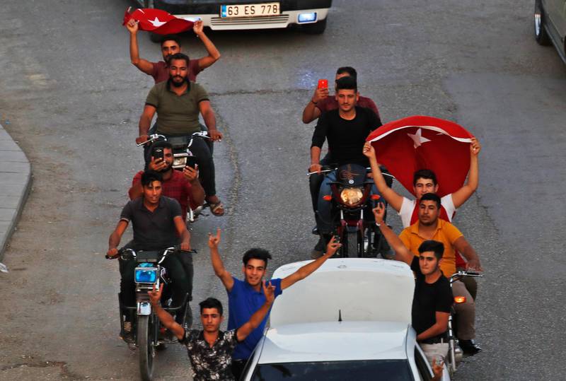 Youths celebrate in Akcakale, Sanliurfa province, southeastern Turkey, after the state-run Anadolu news agency reported the northern Syrian town of Tal Abyad had fallen to a Turkish military offensive. AP Photo