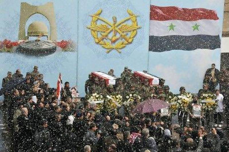 Snow falls as Syrian soldiers carry coffins of their colleagues during a funeral ceremony in Damascus Saturday.