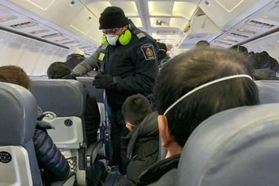 A Royal Canadian Mounted Police officer wearing a mask checks Canadians evacuated from China. Reuters