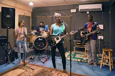 (FILES) In this file photo taken on November 10, 2018, Sangeeta Agnes Hosea (C), lead singer and musician of the Indian band Midnight Poppies, poses for a photograph with her smartphone during a jam session in Bangalore. Sangeeta uses her smartphone to record her songs and also to promote the band on social media. / AFP / MANJUNATH KIRAN
