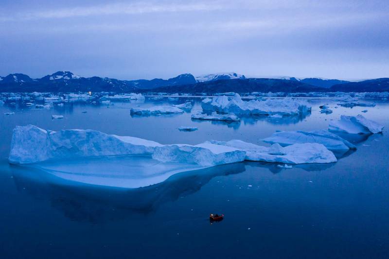 A boat navigates at night next to large icebergs near the town of Kulusuk, in eastern Greenland. All photos by AP