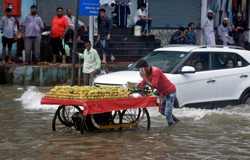A fruit vendor pushes his cart through a water logged road following heavy rains in Mumbai. AP Photo