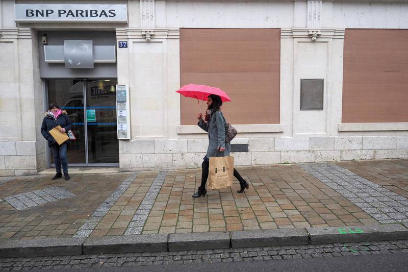A woman walks past a BNP Paribas bank protected by wooden planks, on the eve of a Yellow Vest (gilet jaune) protest, on January 11, 2019 in Bourges.  / AFP / GUILLAUME SOUVANT
