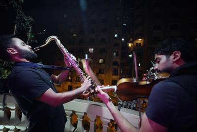 Egyptians Mahmoud Saad (left) plays saxophone and Mohamed Adel (right) violin on their balcony during curfew in Giza, Egypt.  EPA