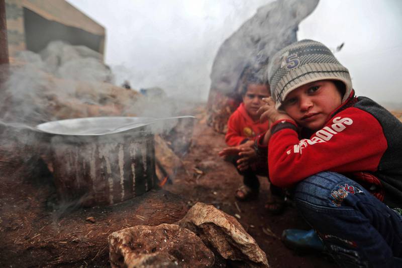 Children warm by the fire in a camp for displaced Syrians near the village of Kafr Uruq, in Syria's northern rebel-held Idlib province. AFP