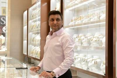 Vishal Dhakan, director of Dhakan Jewellers, stands behind his counter, surrounded by an array of gold items.