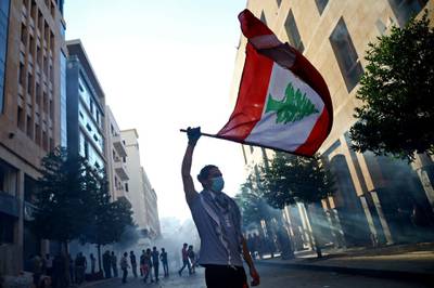 A demonstrator waves a Lebanese flag during anti-government protests that have been ignited by a massive explosion in Beirut, Lebanon August 10, 2020. REUTERS/Hannah McKay