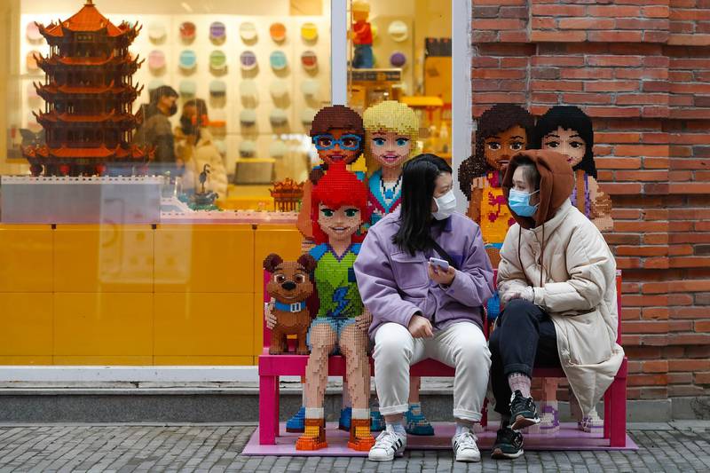 Women wearing protective masks to prevent the new coronavirus outbreak chat with each other outside a Lego store at a re-opened commercial street in Wuhan in central China's Hubei province.  AP