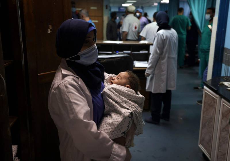 A nurse holds a baby, who was pulled alive from under the rubble while seven other family members perished, at Al-Shifa Hospital, after an Israeli air strike struck al-Shati Refugee Camp without advance warning during the night, in Gaza City. AFP