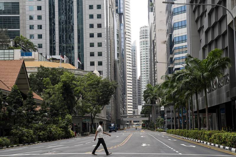 SINGAPORE, SINGAPORE - APRIL 7: A man crosses an empty road in the central business district on the day a 'circuit breaker' takes effect on April 7, 2020 in Singapore. The Singapore government will close all schools and most workplaces and limit social interactions and movement outside homes for at least a month to stem the spike in local coronavirus (COVID-19) cases. (Photo by Ore Huiying/Getty Images)