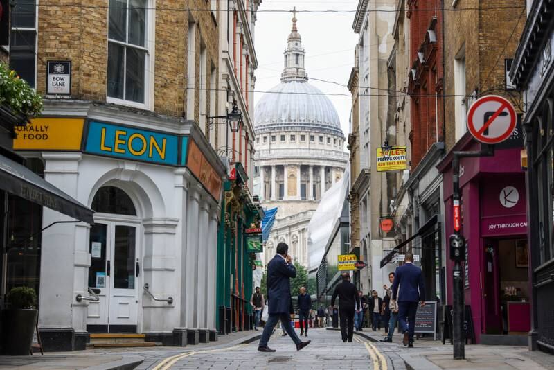 A pedestrian walks along Watling Street in view of St. Paul's Cathedral, central London.