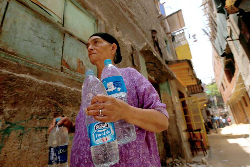 A woman carries bottles of water in Al Assal, one of the oldest slums in the Shubra district of Cairo. residents have been offered new homes away from the dangerous area. Amr Abdallah Dalsh/Reuters
