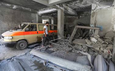 A man walks past a damaged mini-van that was used as a make-shift ambulance amidst debris in the garage of a hospital damaged after a reported air strike in Jisr Al Shughur in the northeastern Syrian Idlib province on July 10, 2019.  AFP 