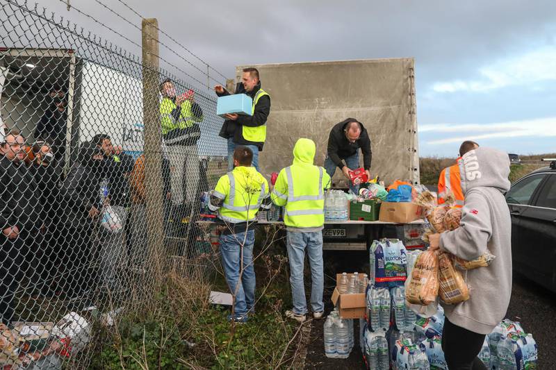 Volunteers distribute fresh food and supplies over a perimeter fence to truck drivers at Manston airport in Manston, U.K. Routes to Dover, Britain's busiest cross-channel port, have been choked for days after France shut its border with Britain, blaming an outbreak of a novel strain of the coronavirus.  Bloomberg