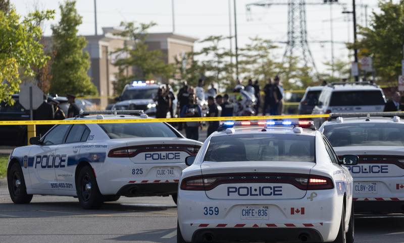 Police officers gather at the scene of a shooting in Mississauga, Ontario, Monday, Sept.  12, 2022.  A Toronto police officer has been fatally shot and a suspect is in custody after two separate shootings left two dead and others injured in the Greater Toronto Area on Monday afternoon.  (Arlyn McAdorey / The Canadian Press via AP)