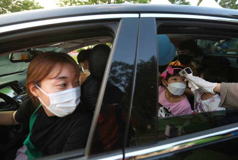 A young girl has her temperature checked as she arrives to watch a drive-in concert at the Gyeongbok Palace car park in Seoul, South Korea. AP Photo