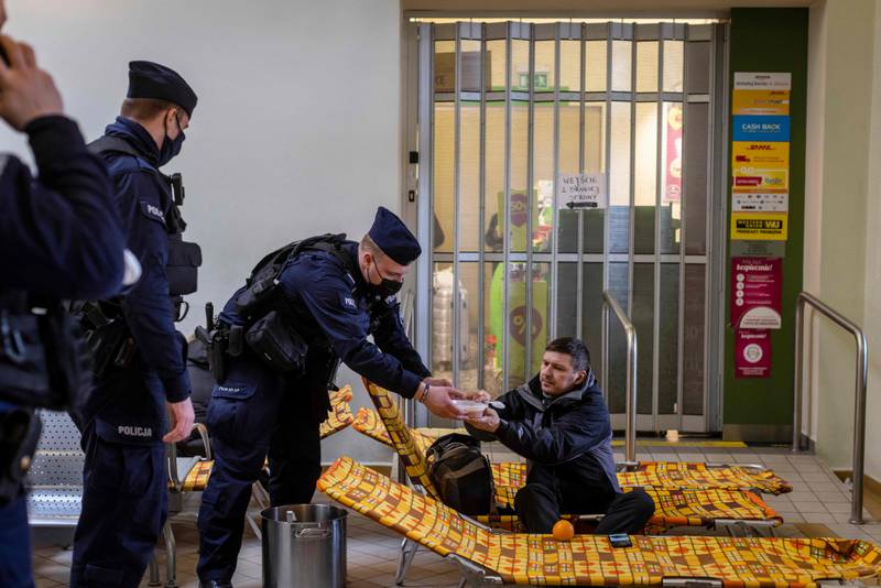 A Polish police officer serves soup to a Ukrainian man in the main railway station of Przemysl which has been turned into a temporary reception centre for refugees. AFP