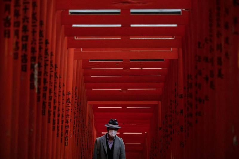 A man with a mask walk through torii gates at the Hie Shrine In Tokyo. The coronavirus has claimed its first victim in the United States as the number of cases shot up in Iran, Italy and South Korea and the spreading outbreak shook the global economy. AP