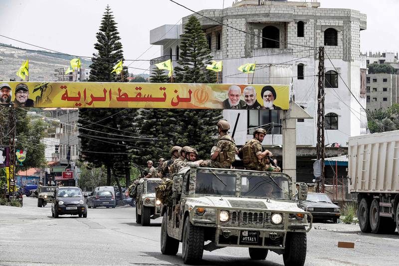 Lebanese army vehicles drive past a banner for the Lebanese Shiite Muslim movement Hezbollah with text in Arabic reading "the flag will not fall", in the southern city of Nabatiyeh, on May 15, 2022. AFP