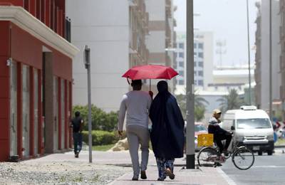 DUBAI, UNITED ARAB EMIRATES , June 9 – 2020 :- People using umbrella during the hot and humid weather at International City in Dubai. (Pawan Singh / The National) For News/Standalone/Online/Stock