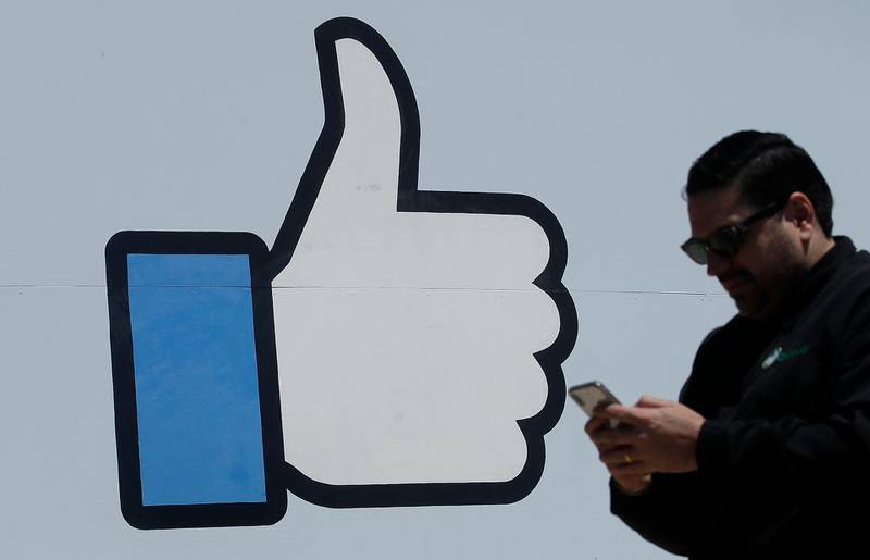 In this April 25, 2019, photo a man walks past the thumbs up Like logo on a sign at Facebook headquarters in Menlo Park, Calif. Facebook reports earning on Wednesday, July 24, 2019. (AP Photo/Jeff Chiu)