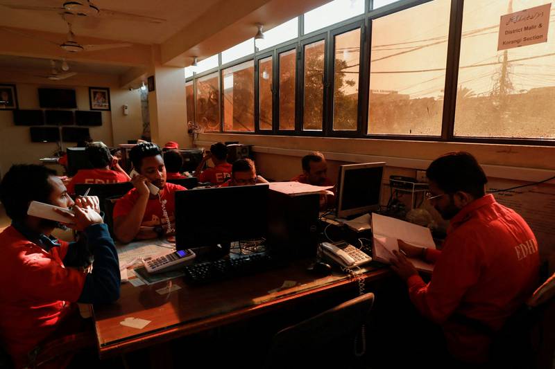 Volunteers with the Edhi Foundation, a social welfare programme, work at darkened desks in Karachi. Reuters