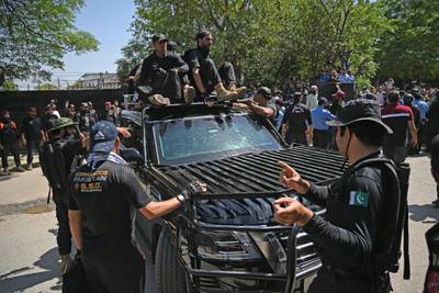Security personnel escort a car carrying Mr Khan as he arrives at the court. AFP