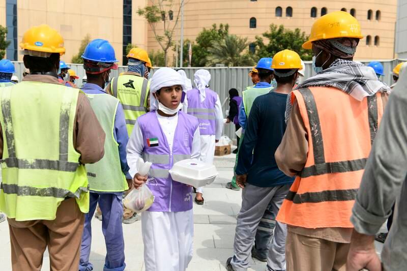 A young volunteer hands out food to construction workers, part of the initiative by the Supreme Council of Motherhood and Childhood, in Abu Dhabi. 
