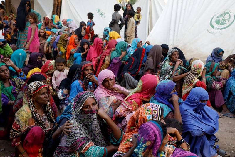 Women affected by the floods wait for food aid at a camp for displaced people in Sehwan. Reuters